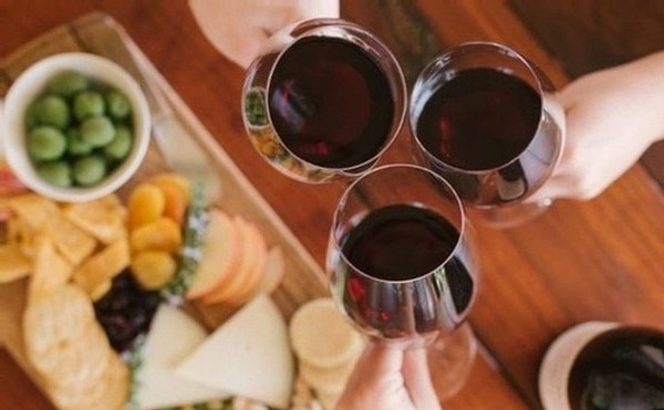 Three wine glasses with red wine toasting over a gourmet cheese plate at our Lunch & Wine Tasting Experience